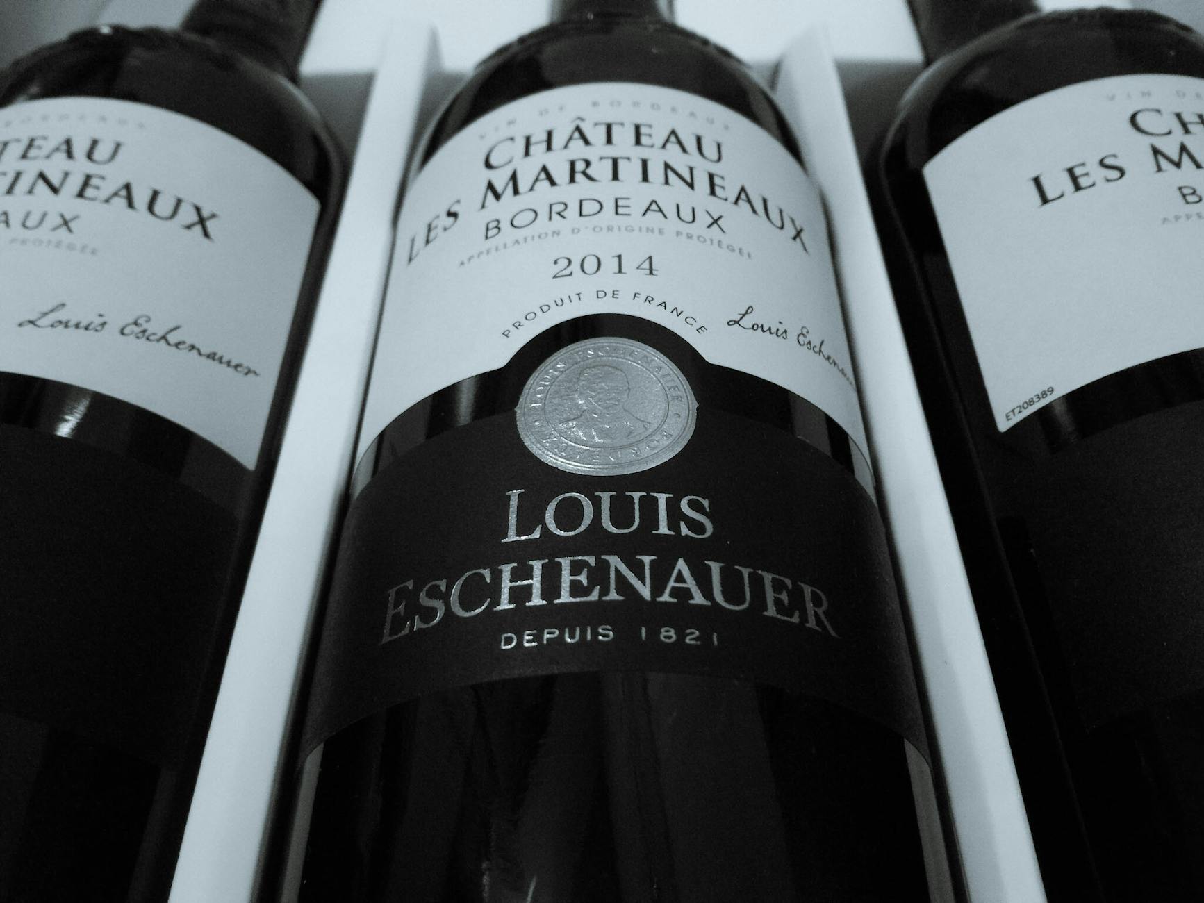 Three bottles of Bordeaux wine displayed prominently, featuring the label of Chateau Les Martineaux by Louis Eschenauer.