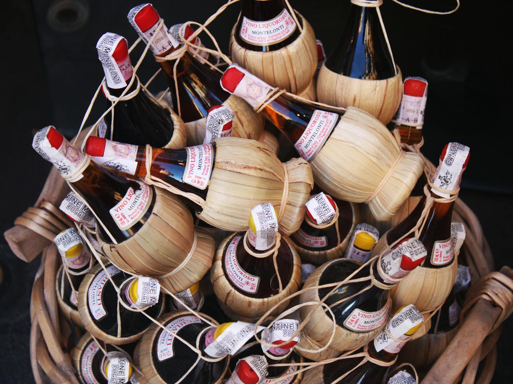 Bottles of Chianti wine wrapped in straw, arranged in a basket, showcasing the traditional packaging style.